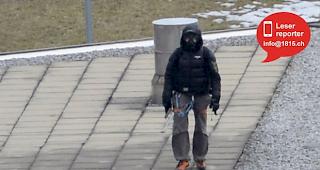 Mit Gasmaske verkleidet und einem Gewehr in der Hand. 