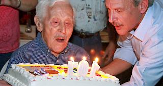 &laquo;Ted Mullers 107. Geburtstag. Sein Sohn reicht ihm den Kuchen, damit er die Kerzen ausblasen kann.&raquo;