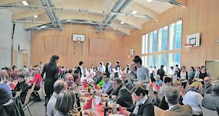 Reger Betrieb. Blick auf Tisch mit geladenen G&auml;sten in der Halle.