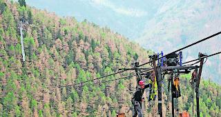 &Uuml;ber den Baumwipfeln. Eine vom Erbauer eigens f&uuml;r diese Br&uuml;cke konstruierte Schwebevorrichtung l&auml;sst die 3 m langen und 60 kg schweren, verzinkten Gitterroste an den Tragseilen dorthin f&uuml;hren, wo sie zum Boden der H&auml;ngebr&uuml;cke zusammengeschraubt werden.  