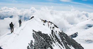 &Uuml;ber den Wolken. Der kleine Grat, der das Kreuz vom eigentlichen Gipfel trennt &ndash; die einzige Passage der ganzen Route, auf welcher man Wind und Wetter ausgesetzt ist.