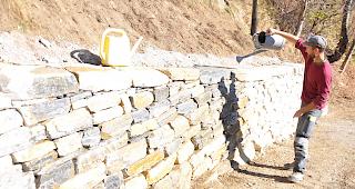 Sobald die Trockensteinmauer nass wird, gl&auml;nzen die Steine in den typischen "Saint-L&eacute;onard-Farben", f&uuml;hrt Bauleiter Robin Locher vor.