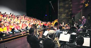 Orchestriert. Die Kinder werden bei der Darbietung im Visper La Poste vom professionellen Orchester von &laquo;singmituns&raquo; unter der Leitung von Hans-Ruedi K&auml;mpfen begleitet. Das Bild stammt von einem fr&uuml;heren Auftritt mit Kindern aus dem ganzen Oberwallis.  