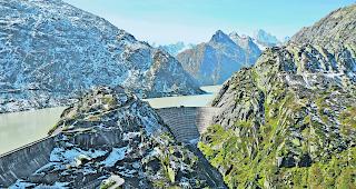 Grimselstausee. Die 90-j&auml;hrige Spitallamm-Mauer (rechts) muss f&uuml;r 120 Millionen Franken ersetzt werden. Sie zeigt Alterserscheinungen. Die Substanz der Seeuferegg-Sperre (links) ist gut. Ein m&ouml;glicher Aufbau beider Mauern um 23m ist projektiert, aber vorerst zur&uuml;ckgestellt. Das w&uuml;rde unter anderem auch eine neue Linienf&uuml;hrung der Grimsel-Passstrasse nach sich ziehen.  