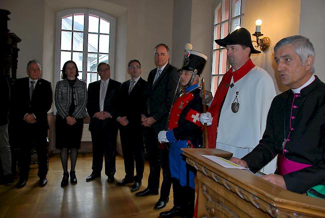 Bischof Jean-Marie Lovey bei seiner Neujahrsansprache. Im Hintergrund lauscht die Walliser Regierung seinen Worten (v. links): Jacques Melly, Esther Waeber-Kalbermatten, Roberto Schmidt, Frédéric Favre und Christophe Darbellay.