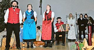 Eine fast heilige Nacht. Das Terzett &laquo;Brigerberg&raquo; mit &laquo;D&rsquo;Liebi isch vom Himmel cho&raquo; mit der Verfasserin des Singspiels, Manuela Lehner-Mutter (in blauer Tracht), begleitet von Marcel Volken. Hinten rechts die beiden Hirten mit dem Engel Gabriel.