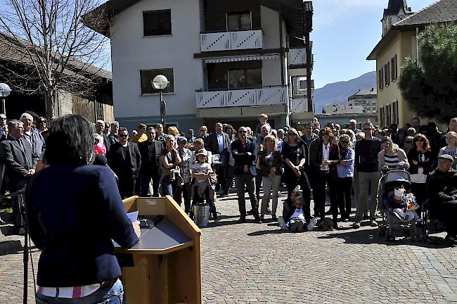 Gemeinderätin Silvia Schmidt bei ihrer Rede auf dem Burgerhausplatz: Sina in weisser Bluse und Sonnenbrille als Zuhörerin.