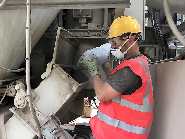 Ein Mitarbeiter von MacRebur füllt in der Asphaltaufbereitungsanlage der Ulrich Imboden AG Restplastik ein.