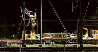 &Uuml;ber den Gleisen. Mit der Hebeb&uuml;hne bringen die Arbeiter die Fahrleitung nach oben zum Mast und warten dann auf ihr Zeitfenster.