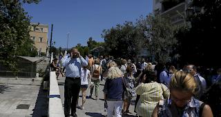Nach einem starken Erdbeben am Freitag in der N&auml;he der griechischen Hauptstadt Athen telefonieren die Leute vor dem Geb&auml;ude, in dem sie arbeiten.