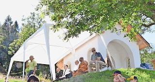 Interreligi&ouml;s. Ein Hindupriester zelebriert eine Feuerzeremonie und im Hintergrund sprechen  die &shy;diversen Glaubensvertreter zu den Anwesenden.