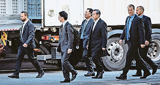 Abgeschirmt. Personensch&uuml;tzer begleiten Aussenminister Wang Yi bei seiner Ankunft in Visp.