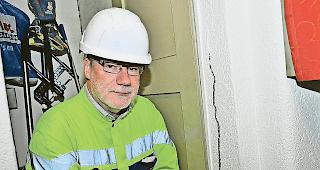 Entstandene Sch&auml;den. Martin Hutter zeigt auf Risse im Innern des Geb&auml;udes.