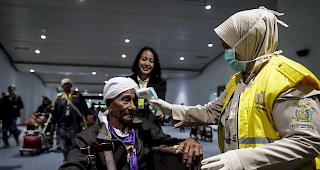 Ein indonesischer Quarant&auml;nebeamter misst die Temperatur eines Passagiers bei seiner Ankunft am Flughafen.